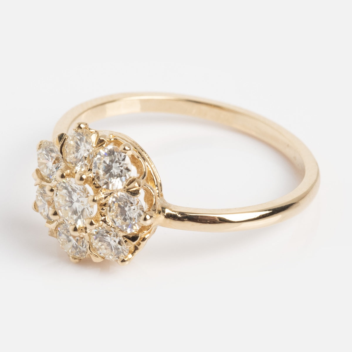 The Amas d'Etoiles Ring is a gold piece featuring a floral cluster design with multiple round, clear gemstones set closely together on top.