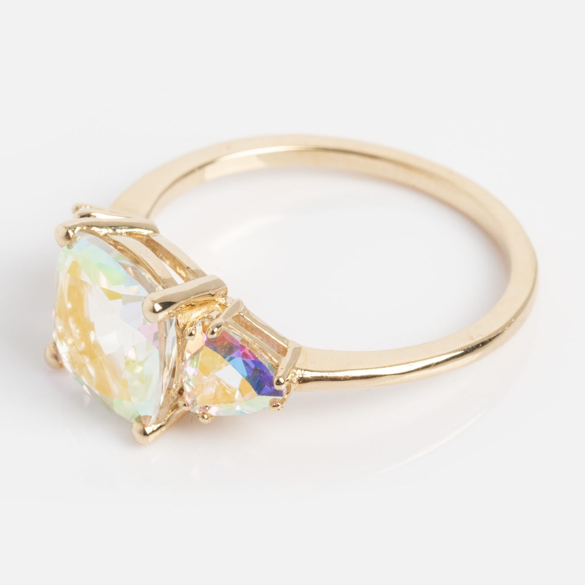 The Seraphina Ring features a large, oval iridescent gemstone at its center, accented by two smaller triangular stones, all set on a gold band and displayed against a plain white background.