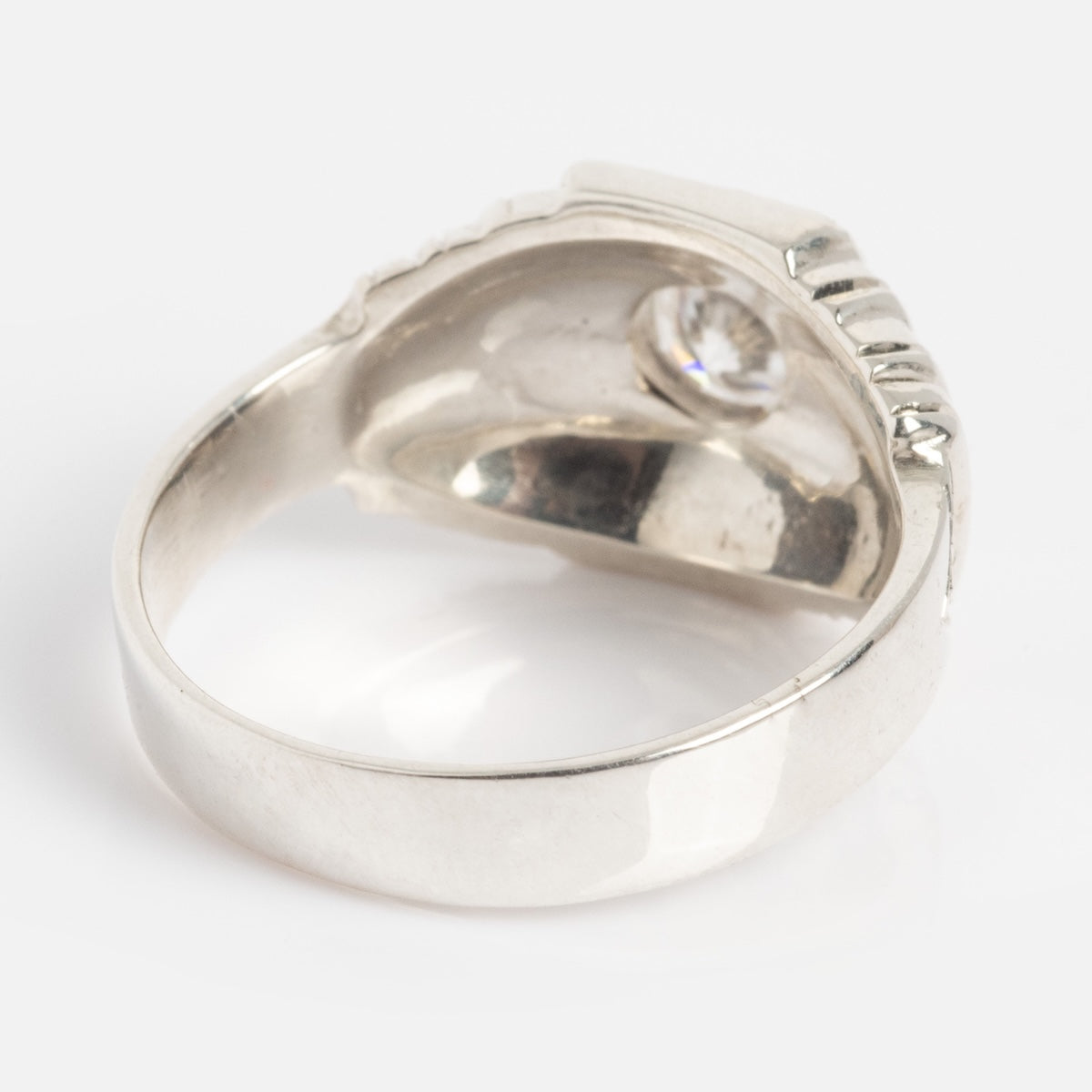 A close-up of the Sacred Ring reveals its smooth, reflective silver interior and a single clear gemstone set at the top.
