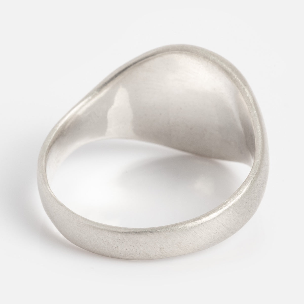 The Till Death Do Us Part Signet Ring is shown from the back on a white background, displaying its smooth, matte silver finish and slightly domed, solid surface.
