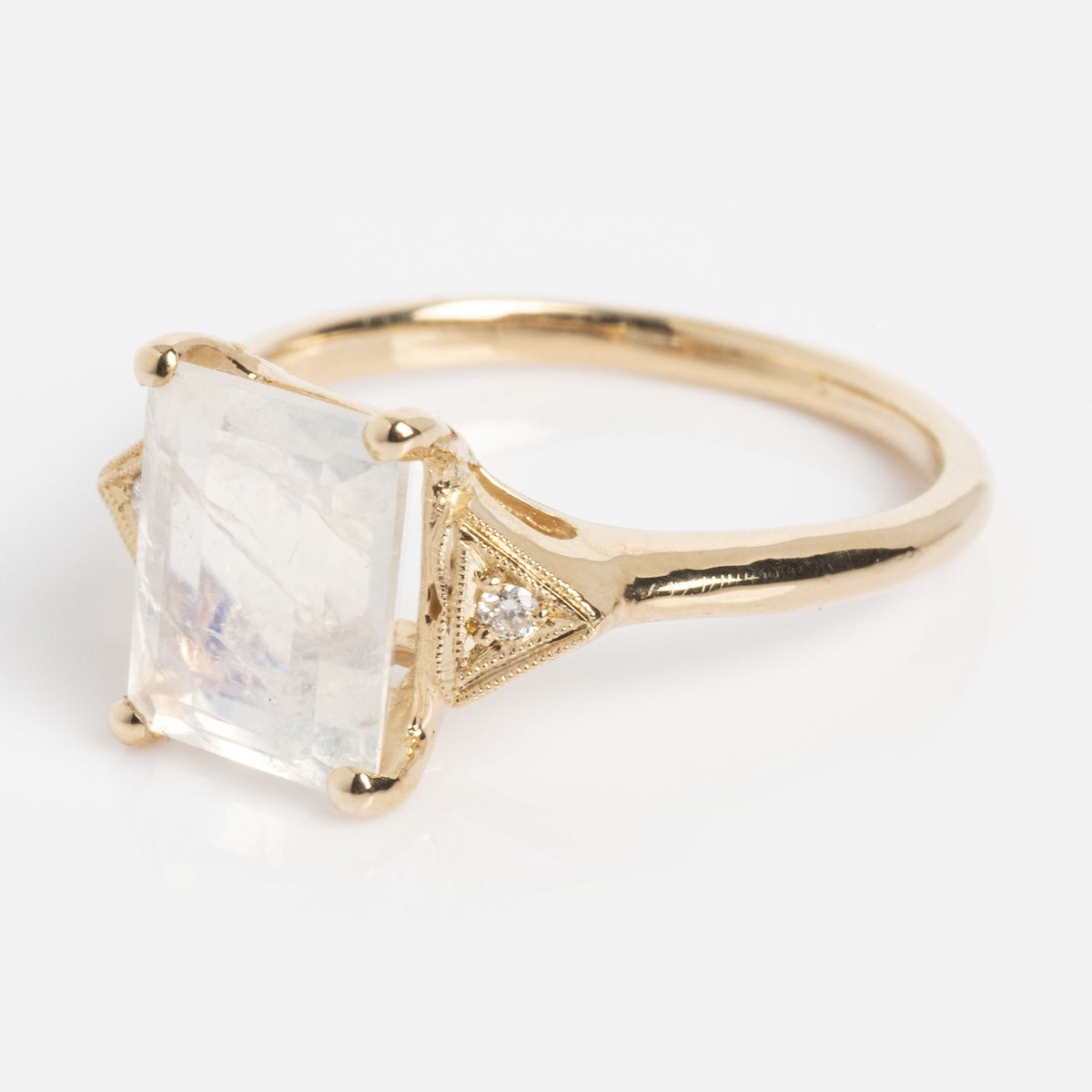 The Celestia Ring is a gold ring featuring a large, rectangular translucent gemstone in a four-prong setting, with small diamond accents on each side of the main stone.
