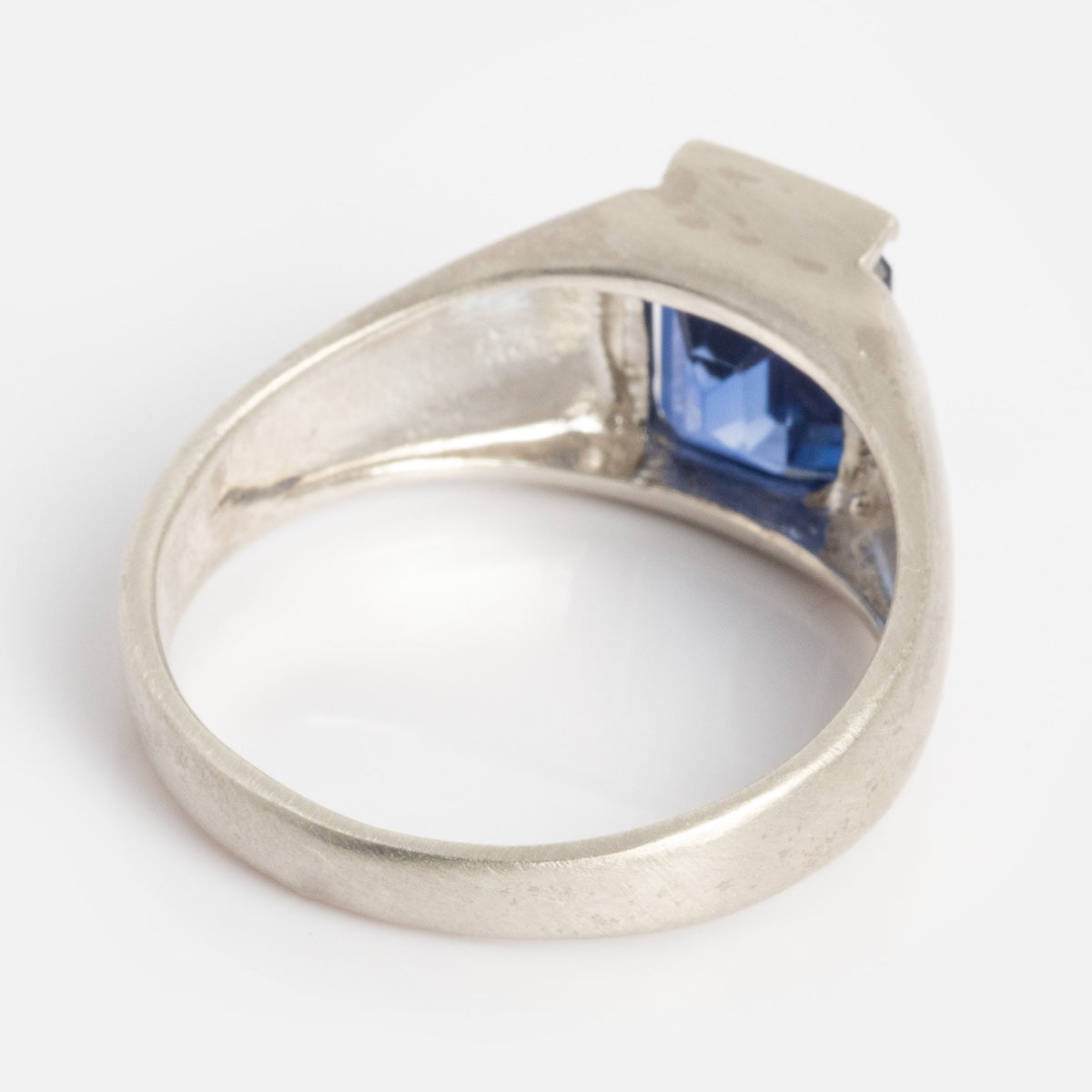 The Legacy Ring is a silver ring with a rectangular blue gemstone in a bezel setting, pictured from the underside on a plain white background.