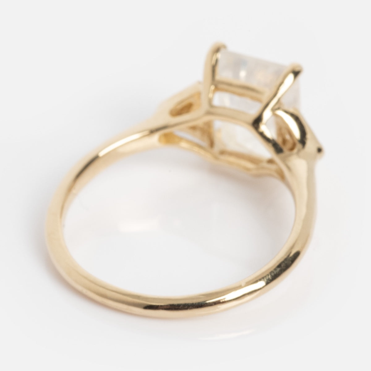 The Celestia Ring features a square, translucent gemstone set in a raised prong setting on a gold band, shown against a white background.