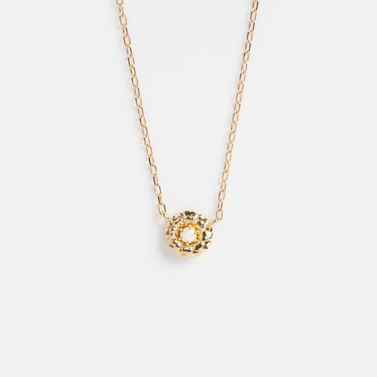 The Solid Gold Birth Flower Bloom Necklace is a delicate gold chain with a textured, round pendant, photographed centered on a plain white background.