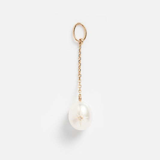 The Solid Gold Statement Charm features a large round white pearl on a delicate 9k yellow gold keychain with a small star detail, displayed against a plain white background.