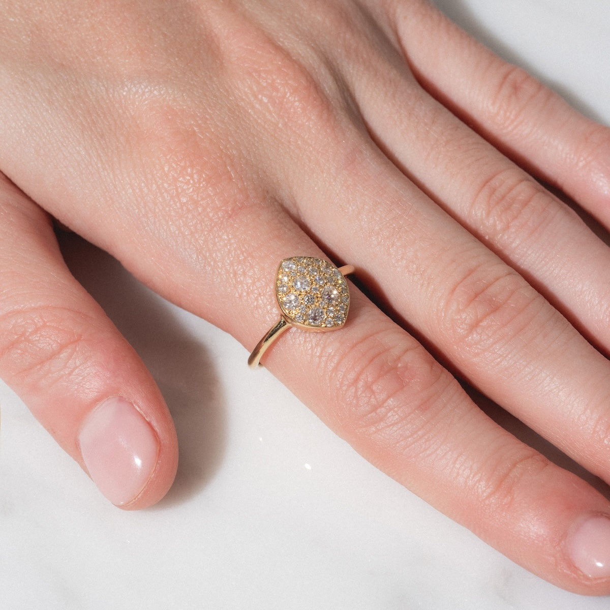 A close-up of a hand on a white surface, wearing the "My Beloved" Soul Ring—a gold band featuring a cluster of small sparkling diamonds on the ring finger.