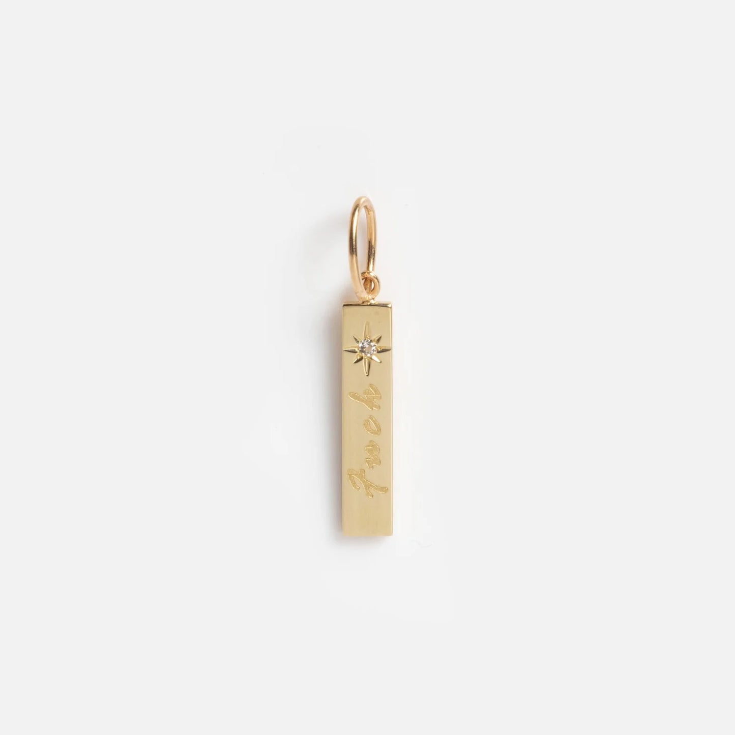 Solid Gold Tiny Fuck Gift Set: A rectangular solid gold pendant engraved with "fuck" in cursive and topped by a small starburst. Attached to a circular loop for hanging, shown on a plain white background.