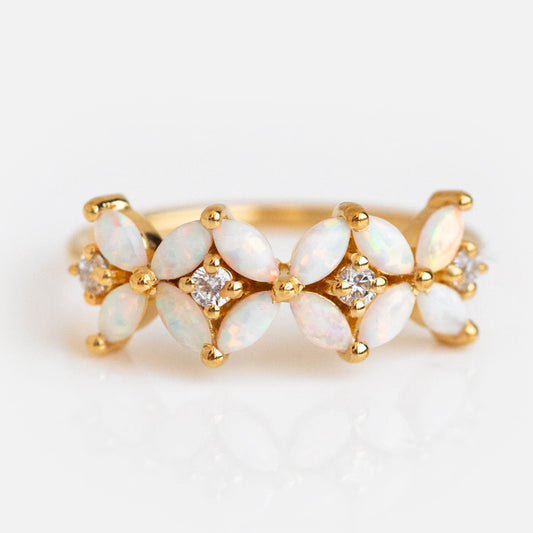 The Opal Fae Ring is a yellow gold piece featuring marquise-shaped opals in a floral pattern, accented by small round diamonds between the opals, all set against a white background.