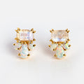 The Gemstone Empress Stud Earrings feature a gold design with square-cut iridescent studs and clusters of teardrop and round opal-like gems, all set against a white background.