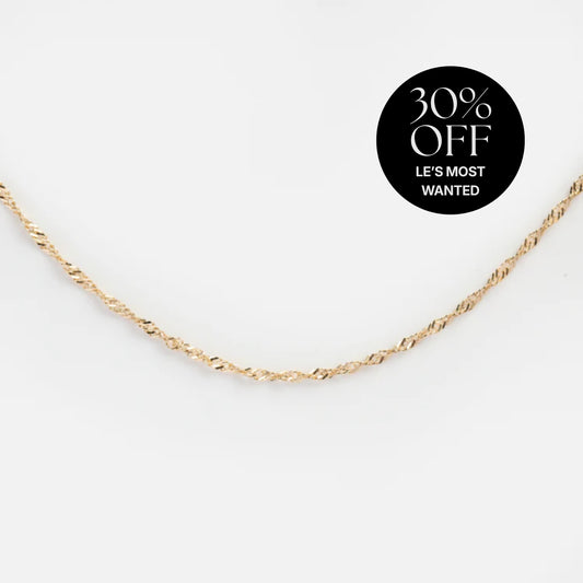 A Solid Gold Twisted Chain Necklace crafted from recycled gold lies on a white background. A black circle at the top right announces 30% OFF LES MOST WANTED, highlighting its elegant and sustainable design.