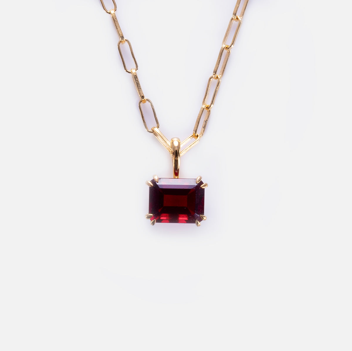 The Born to Shine Birthstone Necklace features a gold paperclip chain with a rectangular, deep red gemstone pendant in a four-prong gold setting, shown against a plain white background.