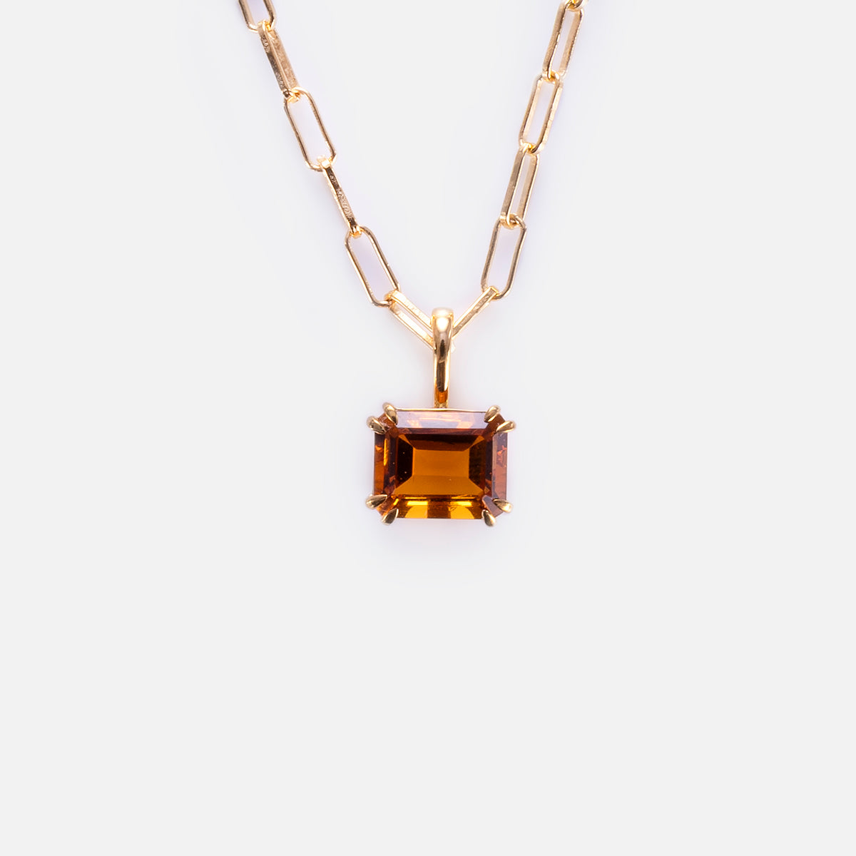 The Born to Shine Birthstone Necklace features a gold paperclip chain with a rectangular, emerald-cut amber gemstone pendant in a gold prong setting, shown on a plain white background.