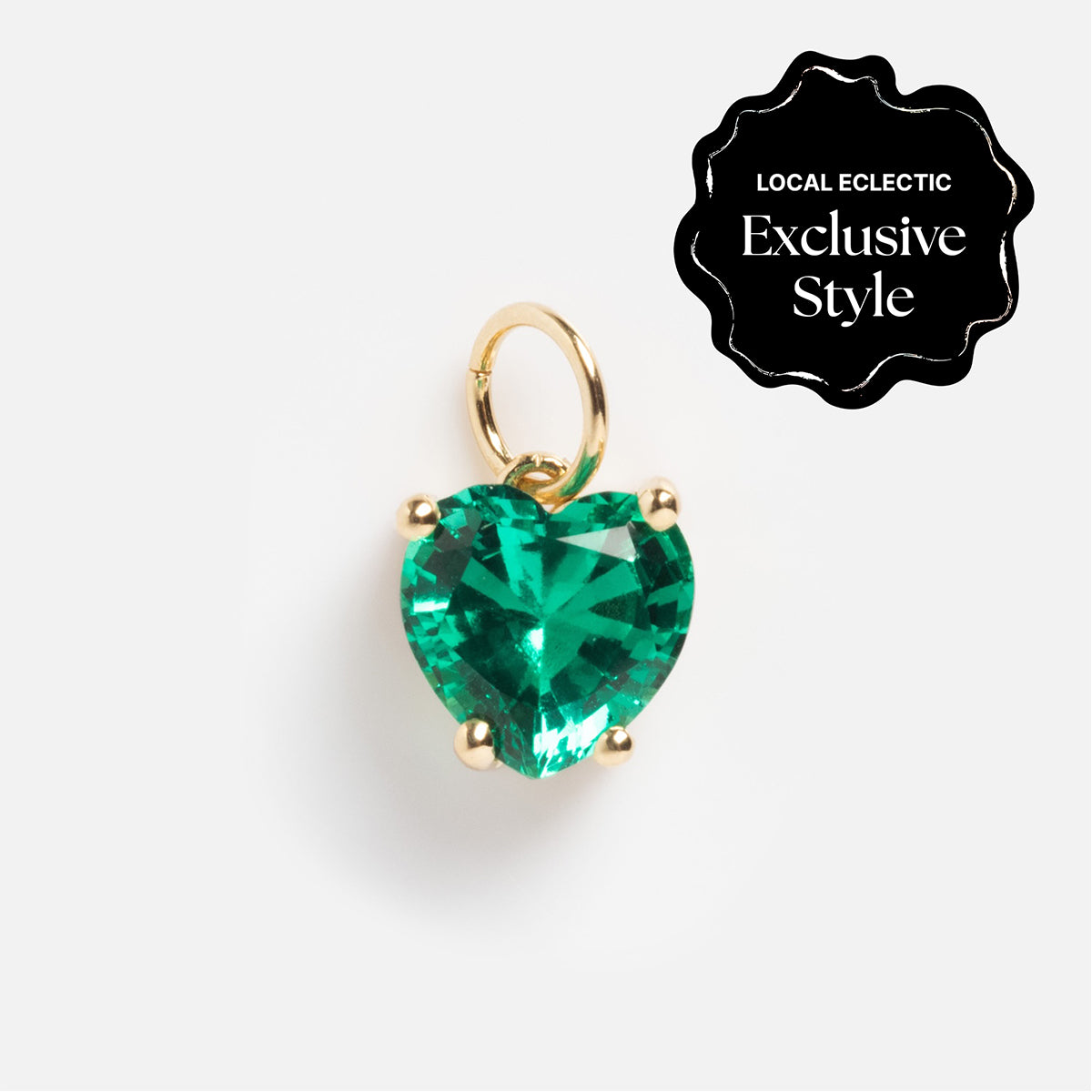The One of a Kind 14k Lab Emerald Heart Charm features a heart-shaped green gemstone with a small hoop on top. A black badge in the upper right corner says LOCAL ECLECTIC Exclusive Style, set against a white background.