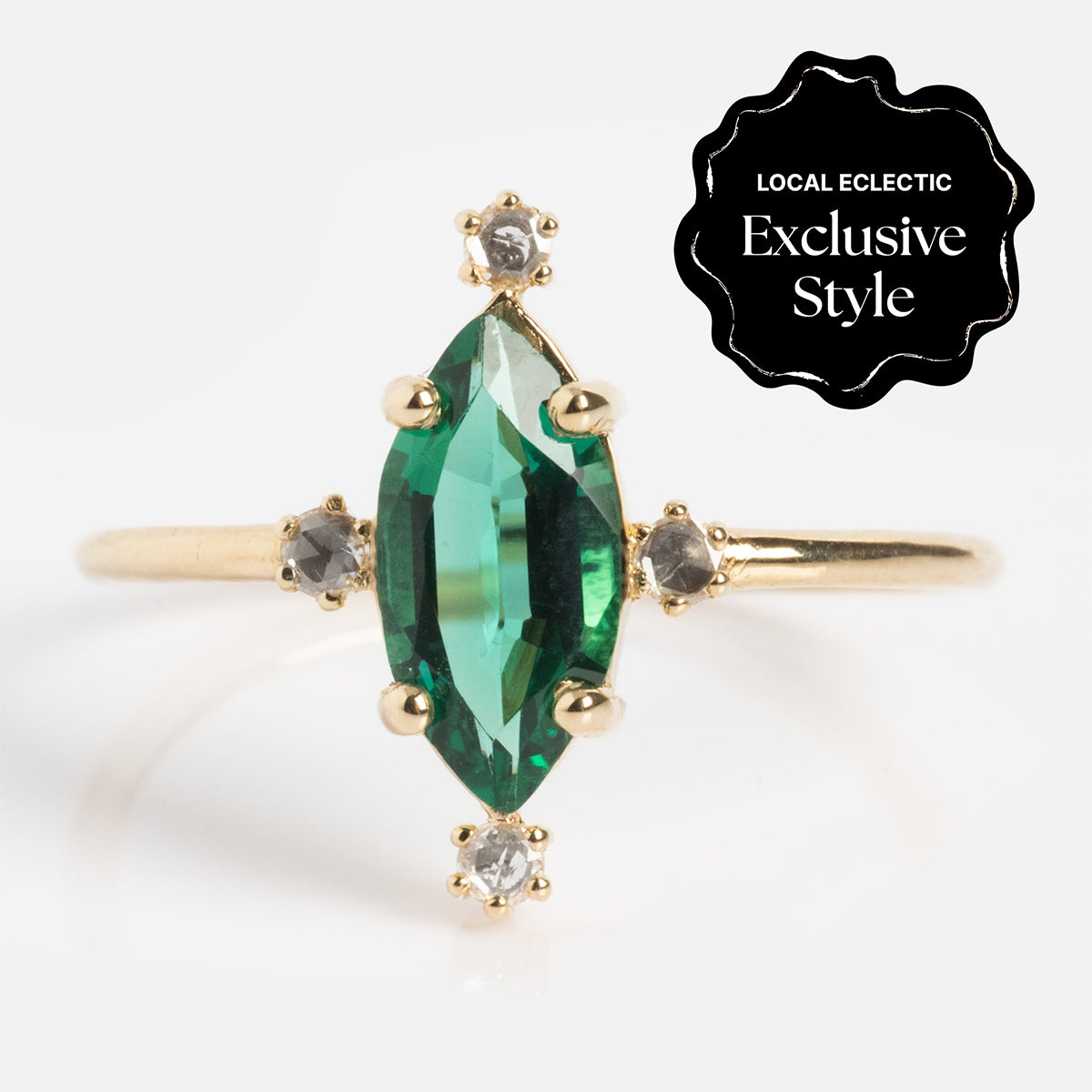 The One of a Kind 14k Marquis Lab Emerald and Diamond Ring showcases a marquise-cut green lab emerald center, accented by four small round diamonds. A black badge in the top right reads “Local Eclectic Exclusive Style.”.