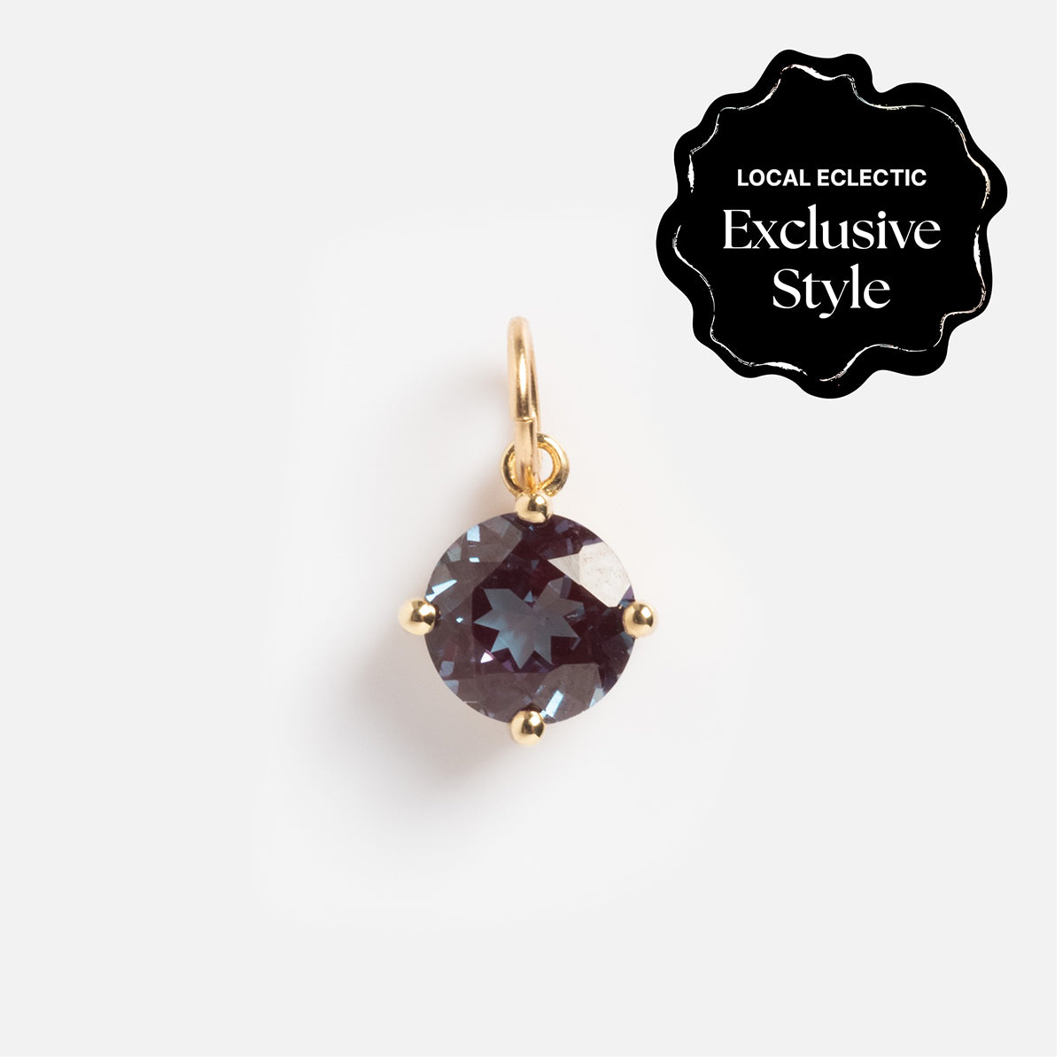The One of a Kind 14k Round Lab Alexandrite Charm features a round dark gemstone in a gold prong setting and bail, shown on a white background. A black badge in the corner reads Local Eclectic Exclusive Style.