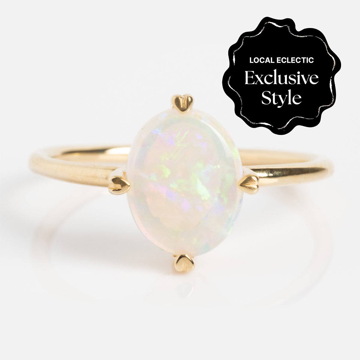 The One of a Kind 14k Heart Prong Opal Ring features an iridescent oval opal set in unique heart-shaped prongs. A black label in the corner reads, Local Eclectic Exclusive Style.