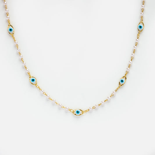 The Dainty Evil Eye Pearl Necklace features a gold plated chain with small white beads and five evenly spaced blue evil eye charms, displayed on a white background.