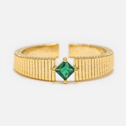 The Serena Ring features a textured gold band with an open back and a square-cut green gemstone set at its center.