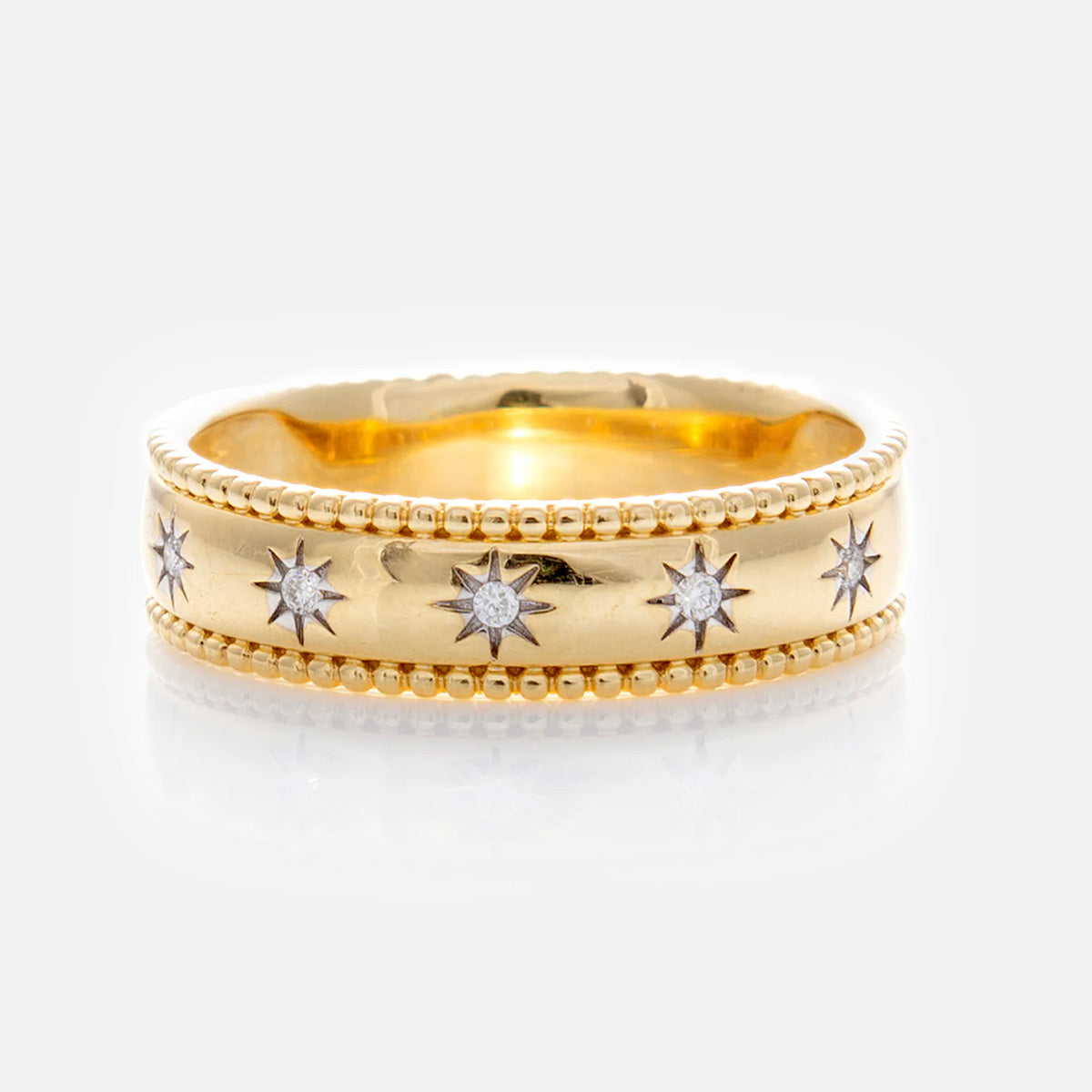 The Solid Gold Bold Star Set Diamond Band features a beaded edge and a row of star-set designs, each centered with an engraved small round diamond, shown on a white background.