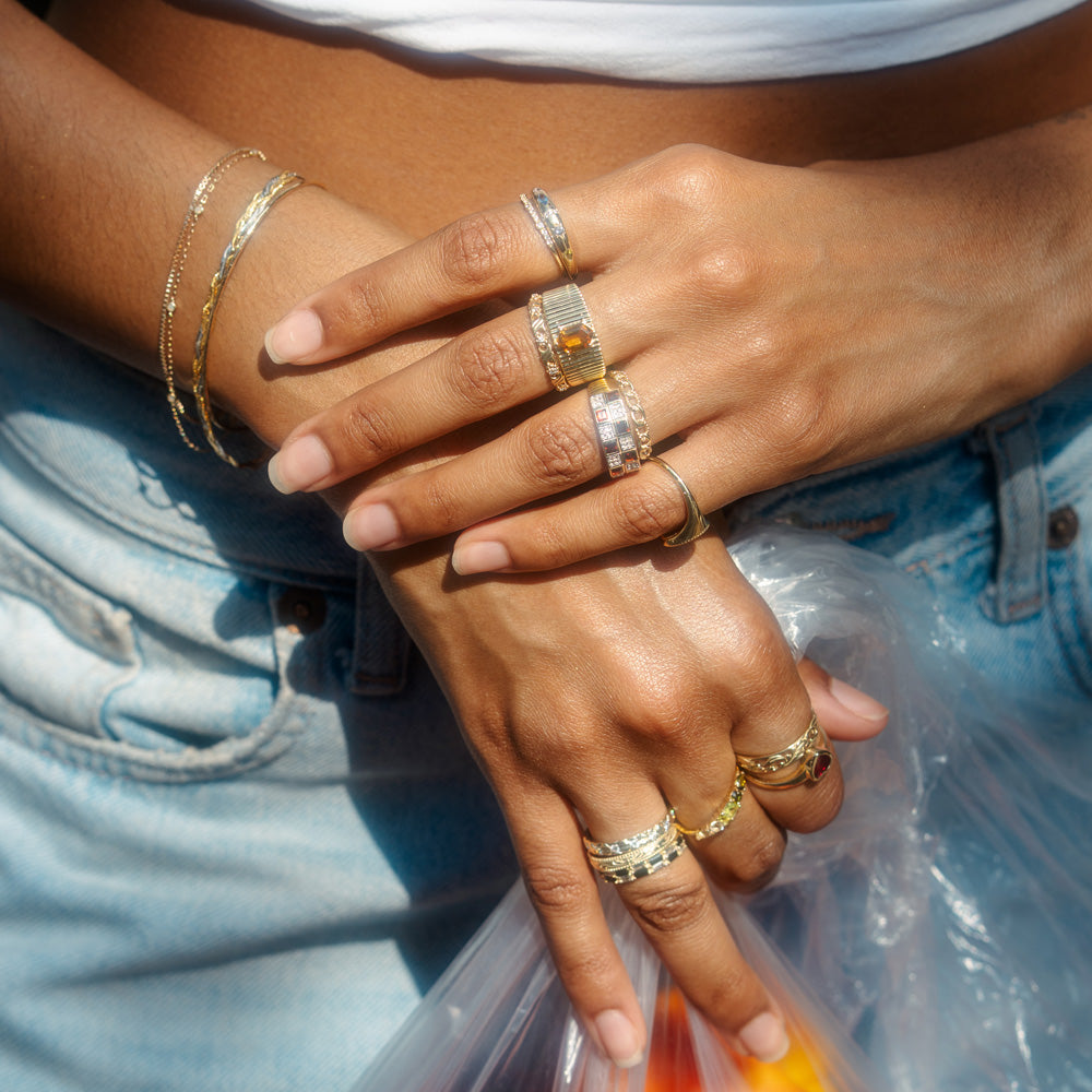 Close-up of hands with multiple rings and bracelets on a denim background