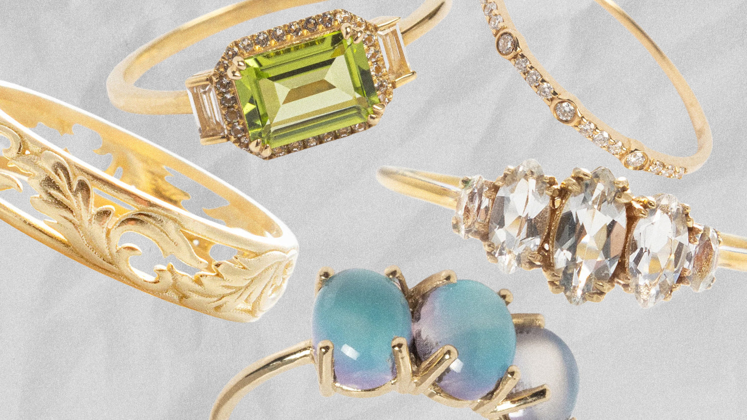 Five gold rings with different designs and gemstones on a light gray background