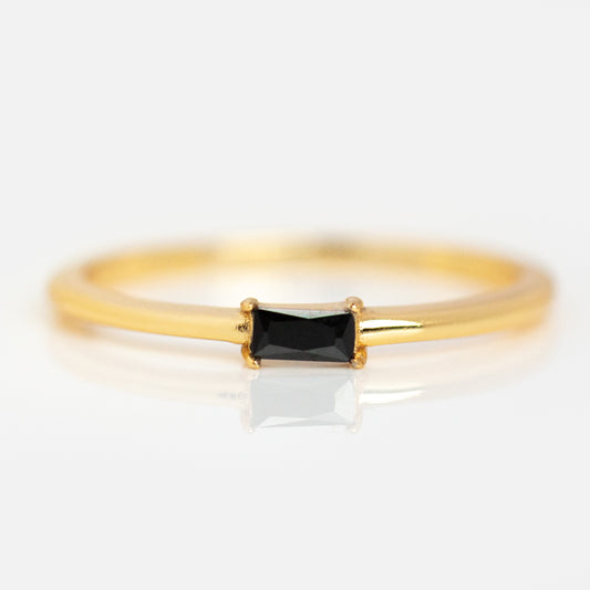 The Baguette Stacking Ring is a delicate 18k gold vermeil piece featuring a small rectangular black cubic zirconia in a minimalist prong setting, shown on a white background.