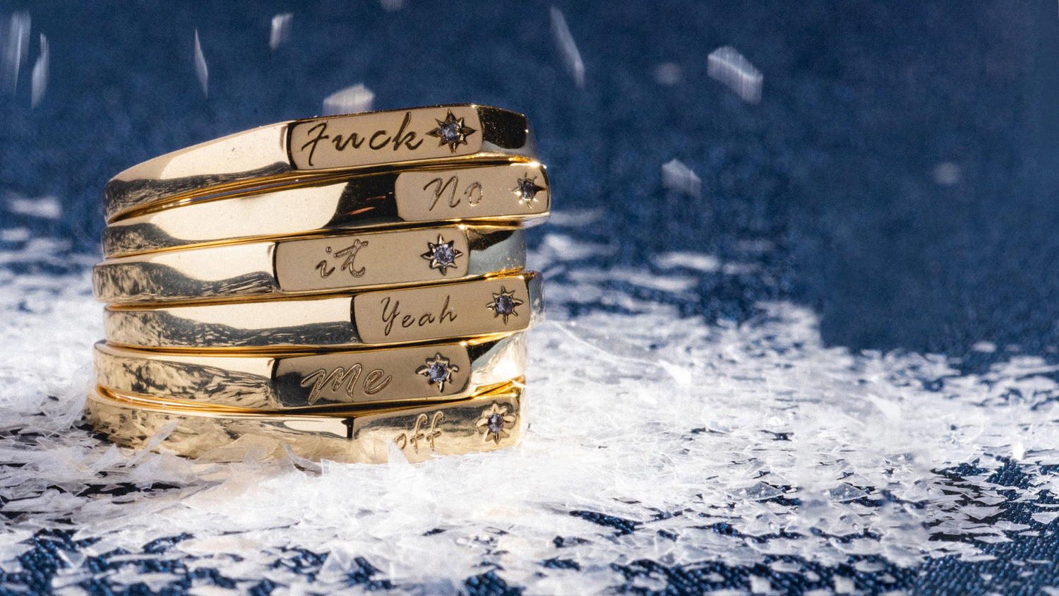 Stack of gold rings with engraved text on a snowy background