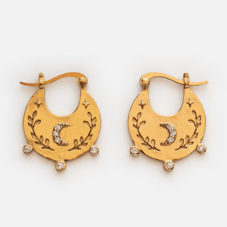 Celestial Bohemian Hoop Earrings in yellow gold feature crescent-shaped hoops engraved with leaves, stars, and a moon, accented by three round gemstones at the base and a sparkling crescent centerpiece.
