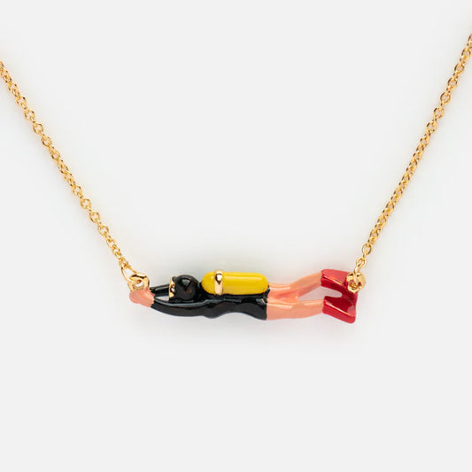 The Scuba Diver Necklace features a yellow gold plated chain and an enamel pendant shaped like a scuba diver in black, yellow, and red with outstretched arms, a yellow tank, and red fins, shown against a white background.