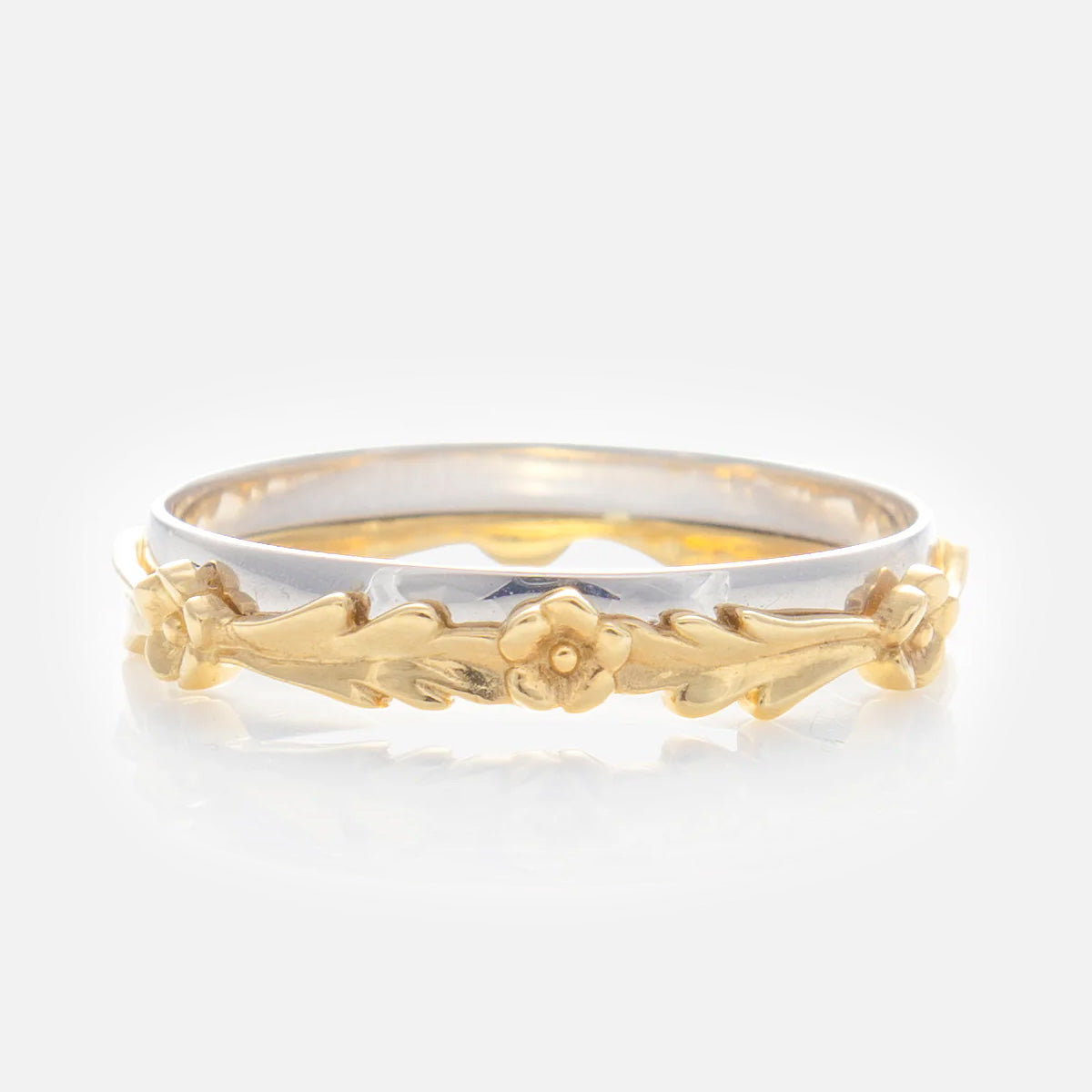 The Solid Gold Mixed Metal Filigree Band features a silver band with an intricate gold floral design of small flowers and leaves in a vintage-inspired style.