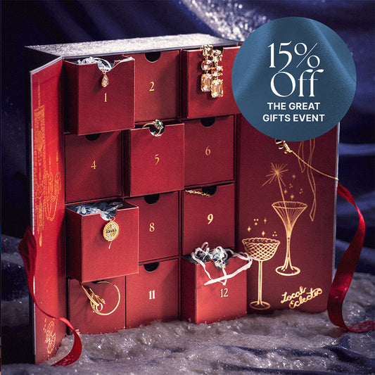 The 2025 Jewelry Advent Calendar is a luxury red box with numbered drawers, revealing gold jewelry inside. It features champagne glass illustrations and sits beside a blue circle displaying “15% Off THE GREAT GIFTS EVENT.” Perfect for holiday gifting.