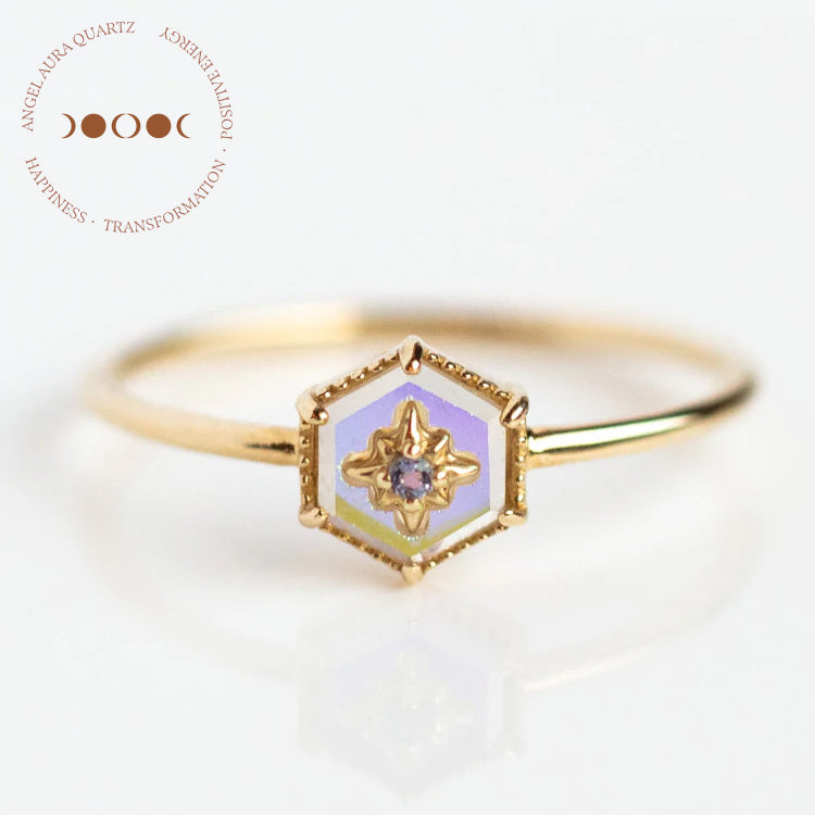 The Solid Gold Crystal Ring for Manifestation features angel aura quartz on a delicate 9k yellow gold band, sample size 7, with natural crystals and a circular logo with text and three crescent moons in the top left corner.