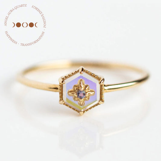 The Solid Gold Crystal Ring for Manifestation features angel aura quartz on a delicate 9k yellow gold band, sample size 7, with natural crystals and a circular logo with text and three crescent moons in the top left corner.