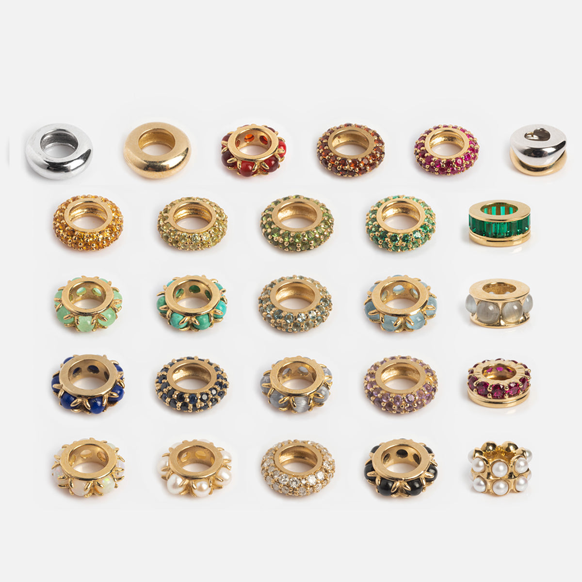 The Solid Gold Anniversaire Charm features 25 decorative round gold and silver metal beads with colorful gem and pearl accents, arranged in a 5x5 grid on a white background—perfect for family or anniversary milestone jewelry.