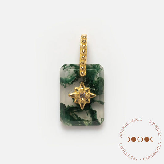 A Solid Gold Crystal Amulet Charm for Manifestation featuring a rectangular moss agate with dark green patterns, star-shaped gold setting, central gemstone, and textured bail. Circle text: AQUATIC AGATE • GROUNDING • CONNECTION.