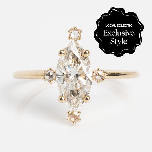 The Asteria Ring is a gold ring with a marquise lab diamond and four small round diamonds at the top, bottom, and sides. Features a "Local Eclectic Exclusive Style" black badge.