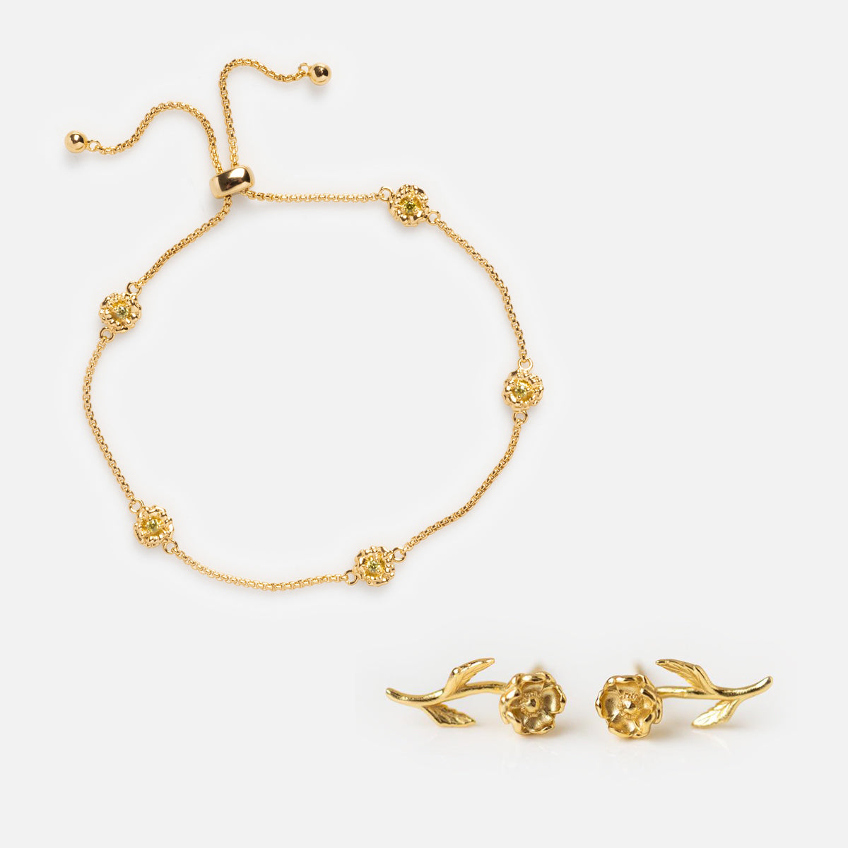 The Birth Flower Gift Set features a gold bracelet with floral accents and adjustable clasp, paired with matching rose-shaped earrings with leaf details, all displayed on a white background.
