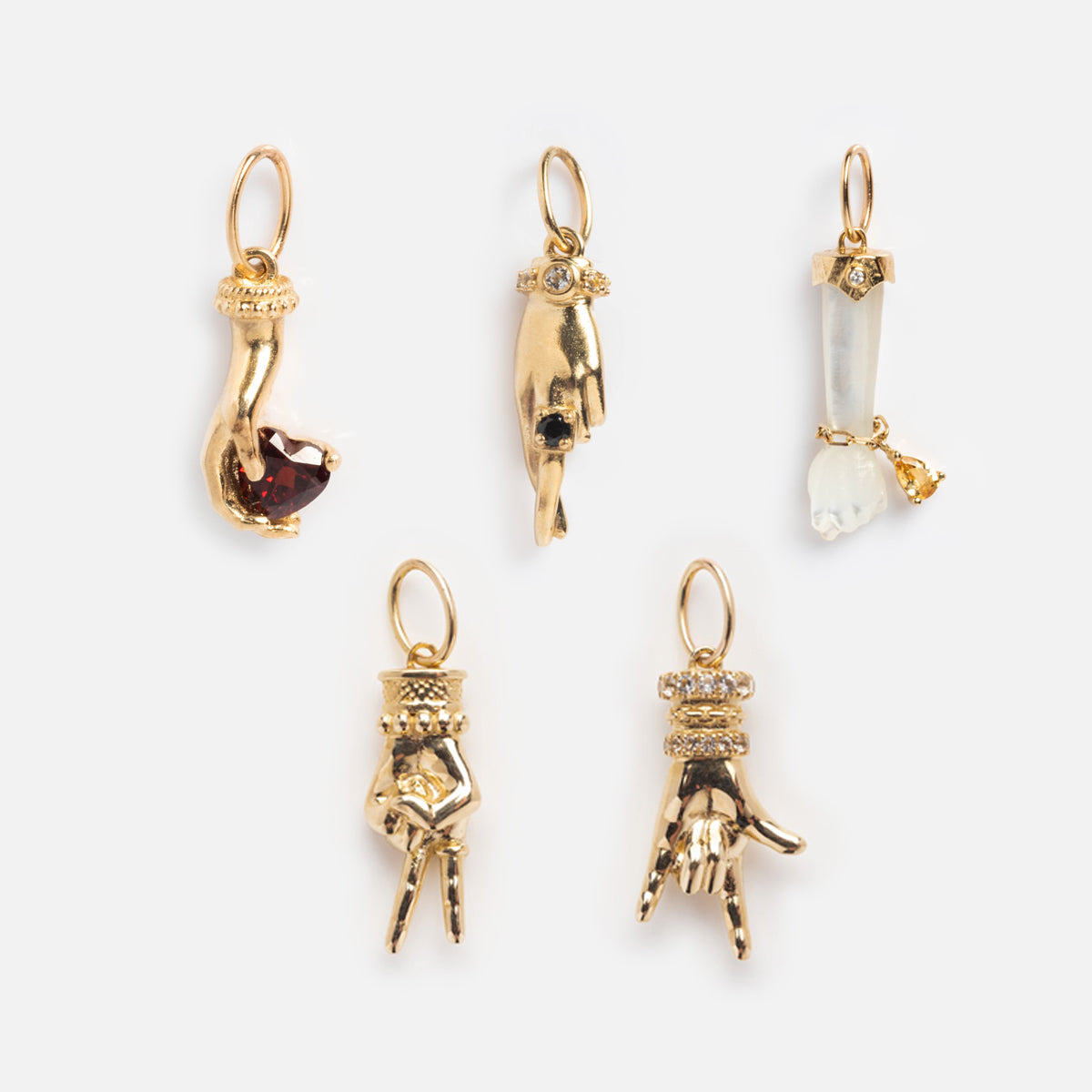 Five Solid Gold Body Language Charms shaped like hands, each with unique gemstones, rings, and gestures—an elegant mix of details showcasing expressive jewelry against a light background.