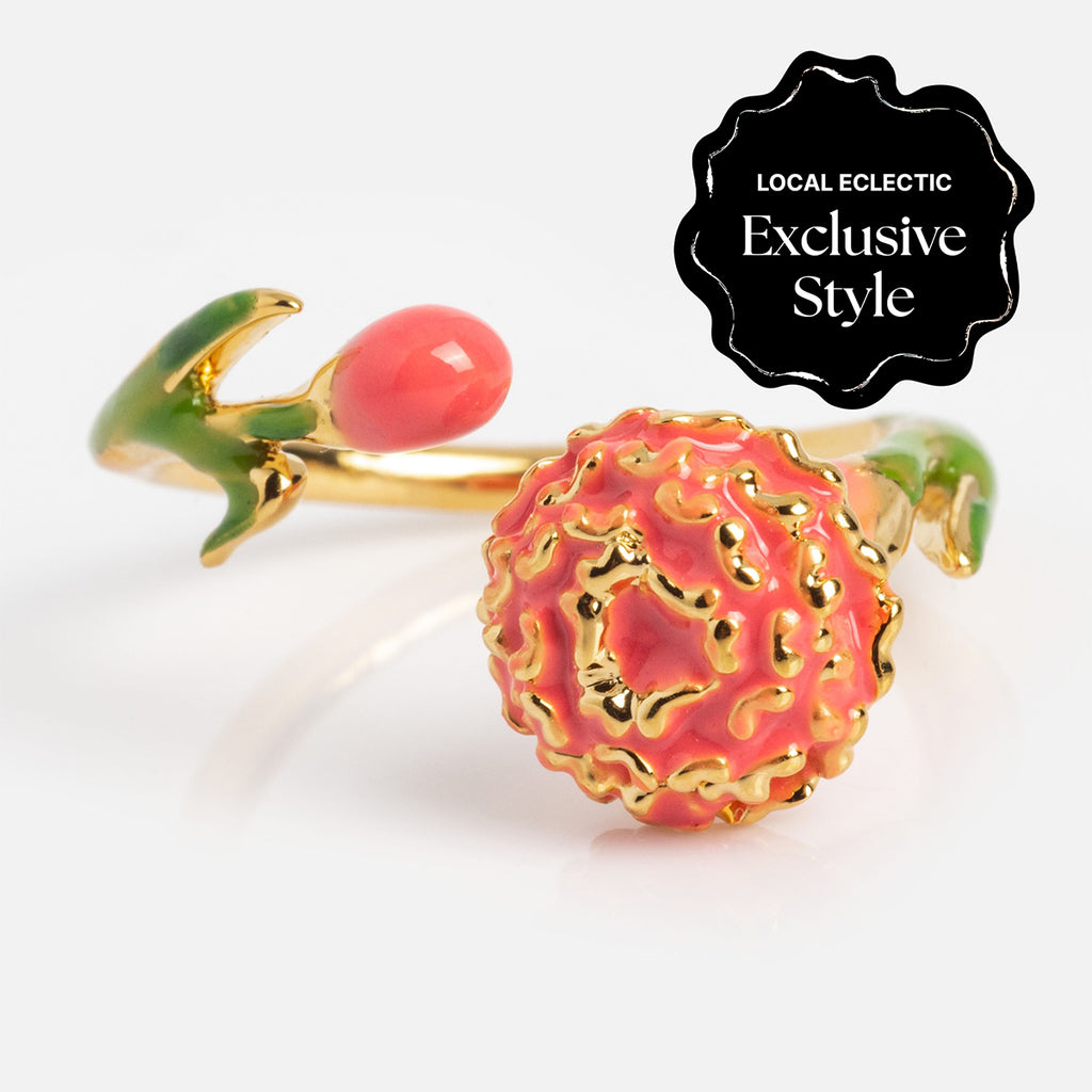 The Blooming Color Adjustable Enamel Birth Flower Ring features a gold band with a coral pink textured flower, matching bud, and green leaves. A black label highlights it as a true Local Eclectic exclusive style.