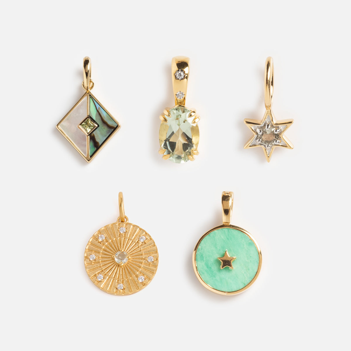 Five Charms by Carrie Elizabeth Jewelry: a diamond-shaped pendant with inlay, an oval with pale gemstone, a star charm, a round sunburst with small gems, and a mint green pendant with star cutout—all on white background.