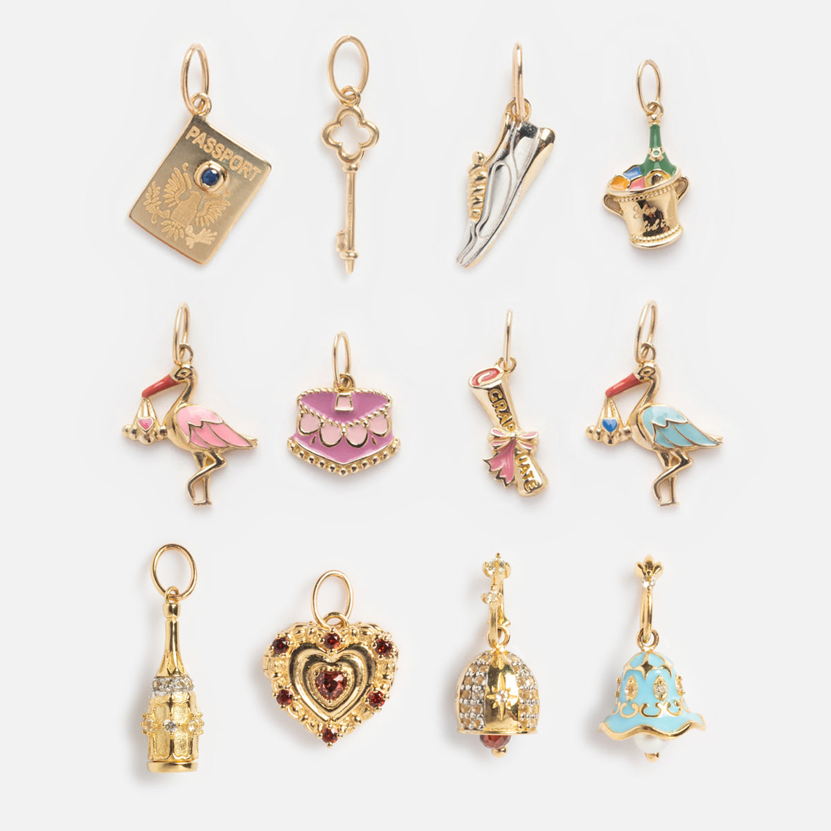 The Solid Gold Celebration Charm is a set of 12 ornate and colorful 9k yellow gold charms, featuring engraved designs like a passport, key, heels, flamingos, handbags, heart locket, crown, blue bell and more.
