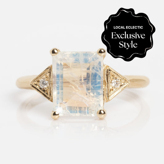 The Celestia Ring features a rectangular faceted moonstone center, flanked by two small round diamonds in triangular side accents. Its slender band ensures a delicate fit. The image label reads "Local Eclectic Exclusive Style.
