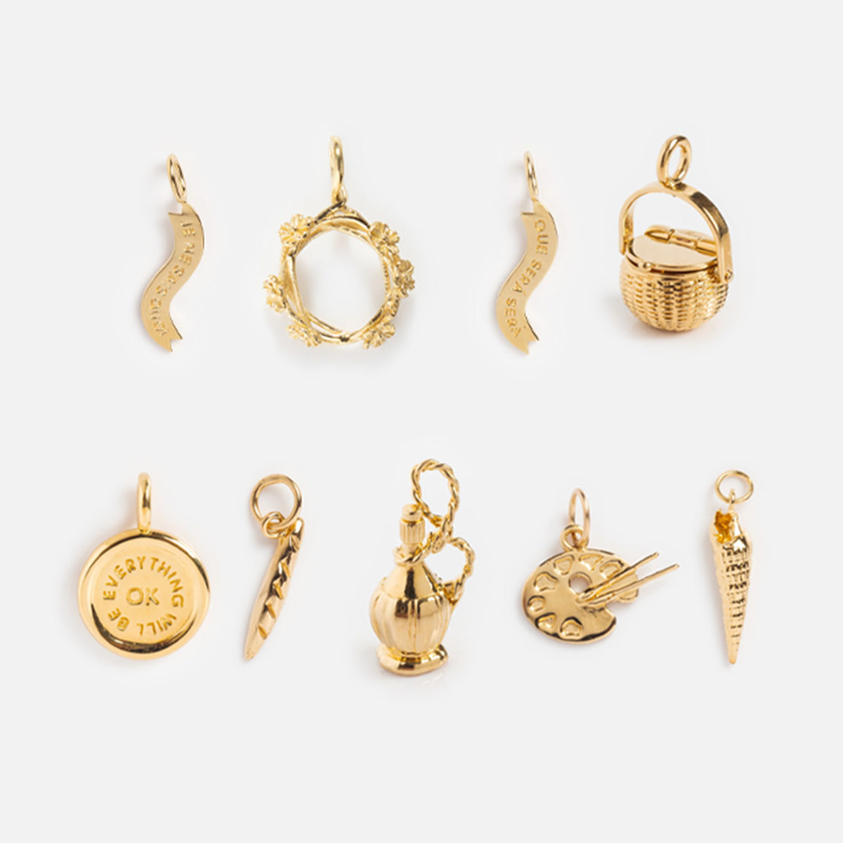 Nine small Charms by I Like It Here Club, crafted with 12k yellow gold plating, are arranged in two rows on a white background, featuring shapes like a wishbone, basket, coin, laurel wreath, olive branch, vase, palette, and carrot.
