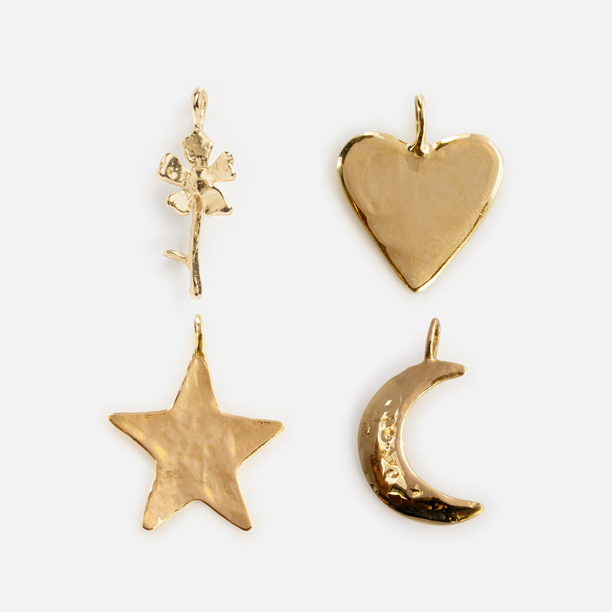 Four gold solid brass Luiny x Local Eclectic Charms—a rose, heart, star, and crescent moon—hand-carved with a textured hammered finish and small loop for attaching to Luiny jewelry, displayed on a white background.