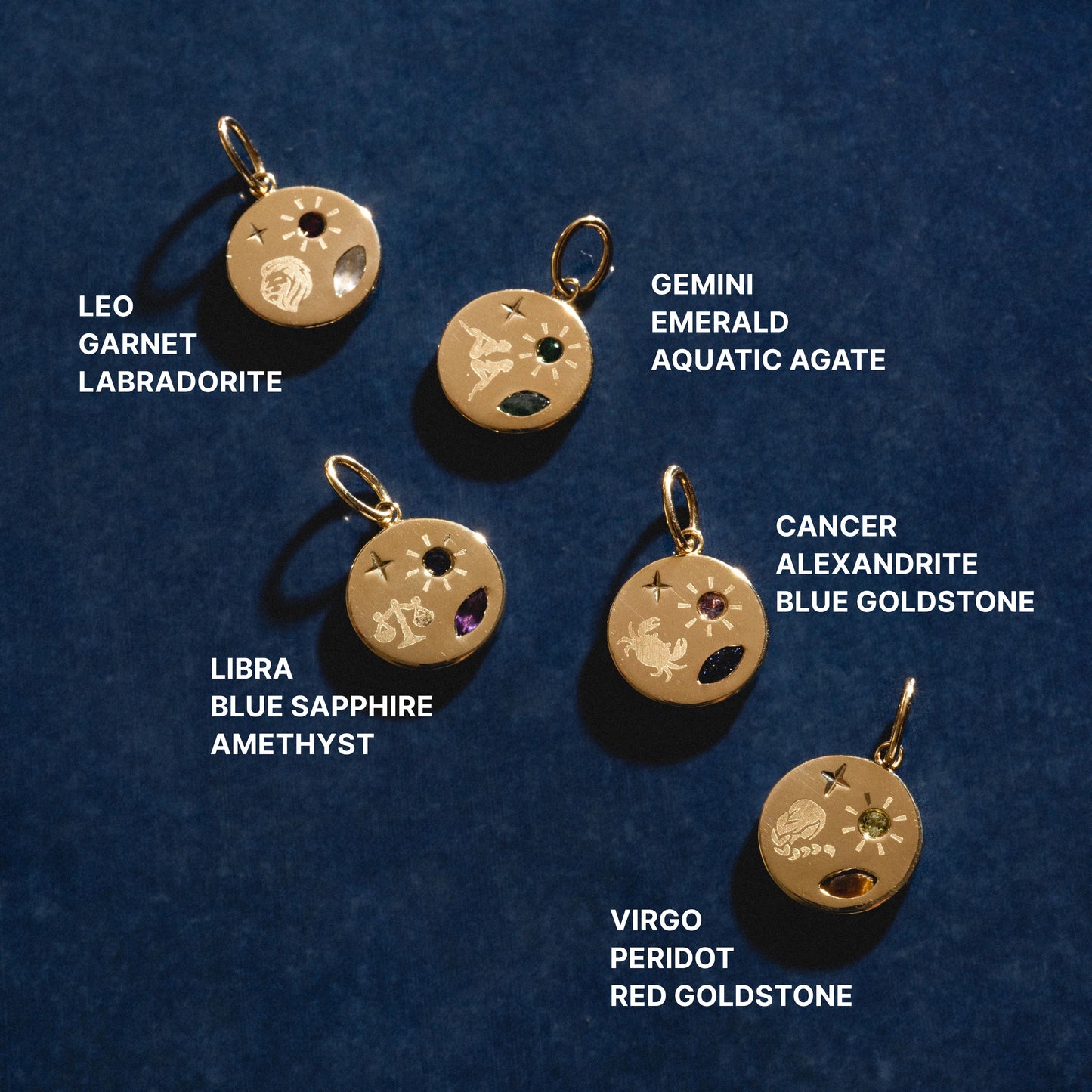 Set of zodiac-themed gold pendants with gemstones on a dark blue background