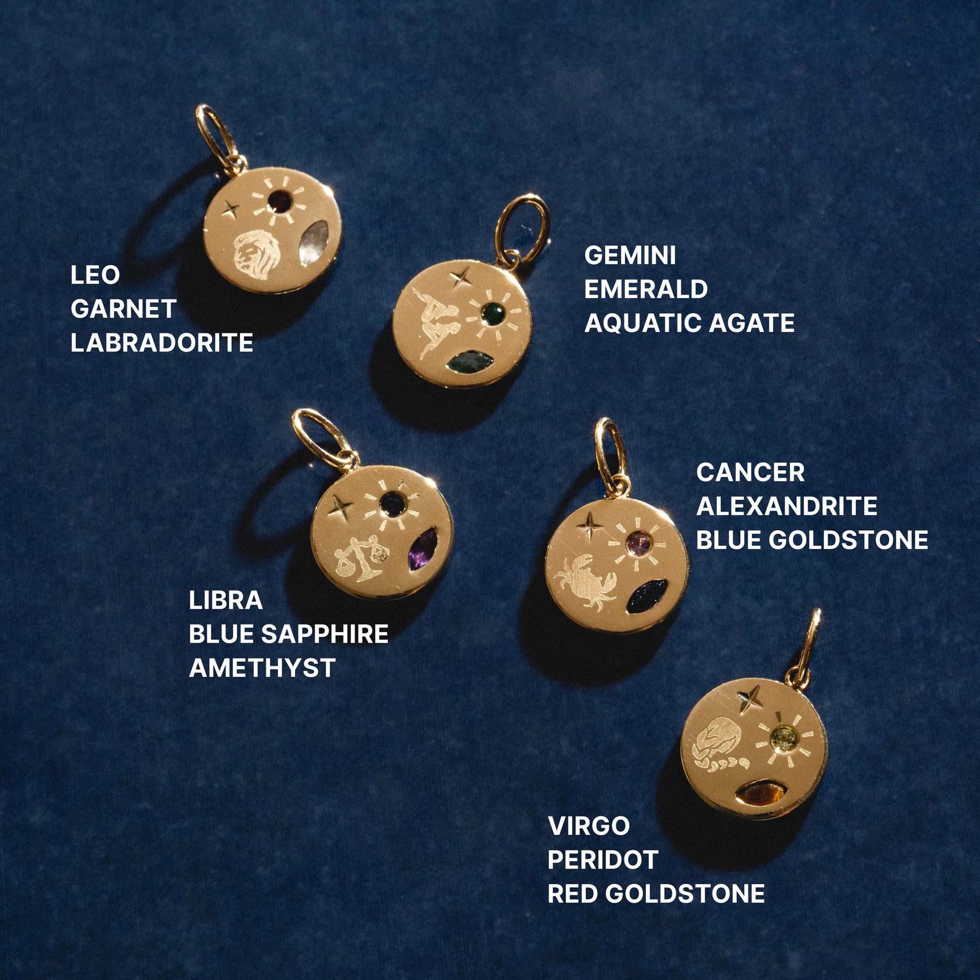 Set of zodiac-themed gold pendants with gemstones on a dark blue background