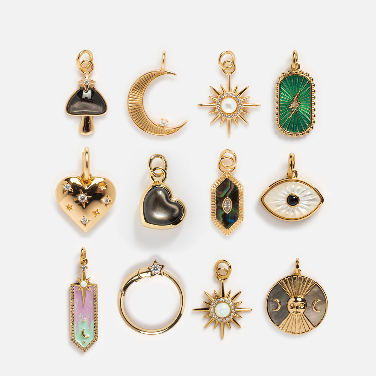 Charms by Elizabeth Stone: Set of 12 celestial charms in 14k yellow gold plating with designs like mushroom, crescent moon, star, heart, eye, sun, and hand—some with mother of pearl enamel and sparkling stones.