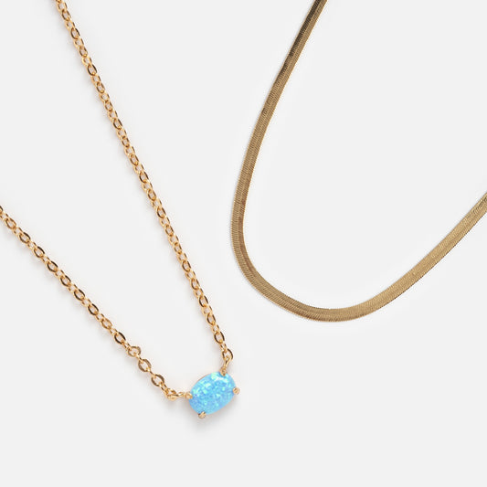 Choose a complimentary necklace with your order over $200—options include a gold chain with an oval blue opal pendant or a smooth herringbone chain, both displayed on a white background.