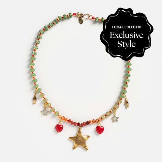 The True North Necklace features green, orange, and red beads with gold star, small hand, and red heart charms. A black label displays "LOCAL ECLECTIC Exclusive Style" in white text.
