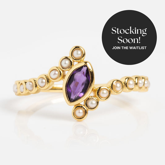 The 2026 February Capsule Floating Amethyst and Pearl Twist Ring features a marquise-cut purple gemstone and pearls in yellow gold vermeil. Shown on white. A "Stocking Soon! Join the waitlist for this birthstone jewelry" badge appears.